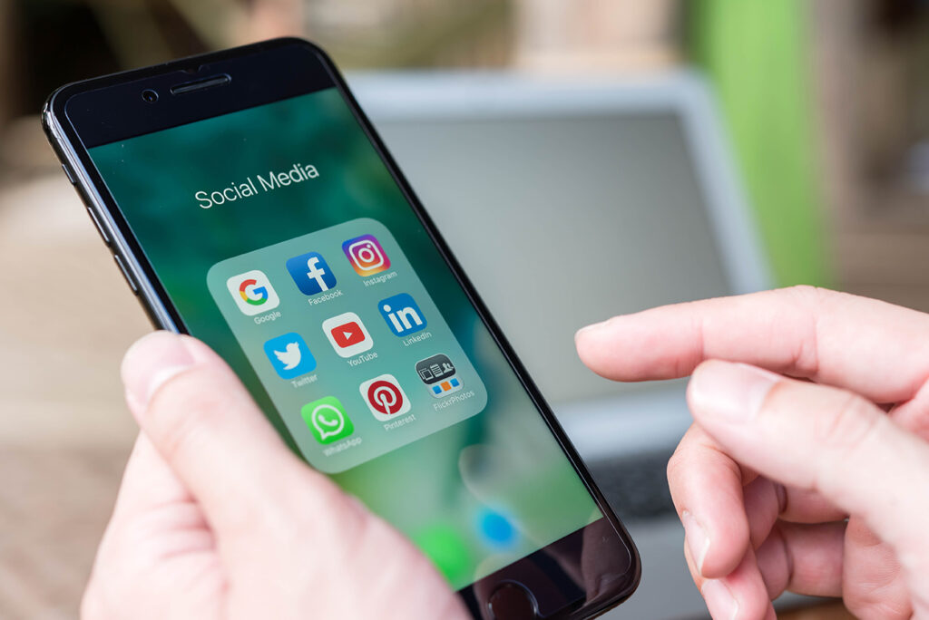Hand of man using Iphone7 Plus with icons of social media on screen, smartphone life style, smartphone era, smartphone in everyday life